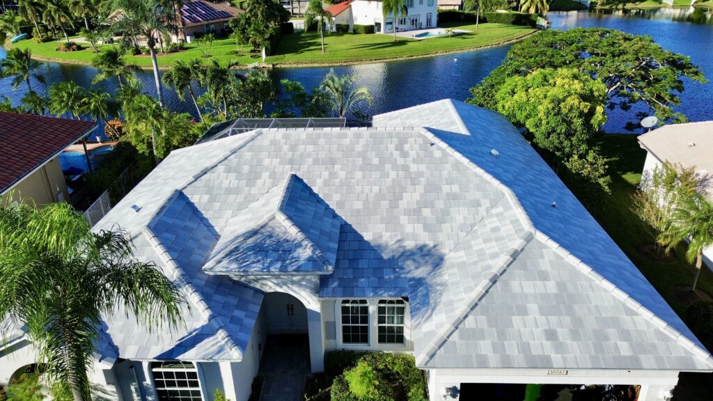 Aerial view of a home with a light gray tile roof near a pond
