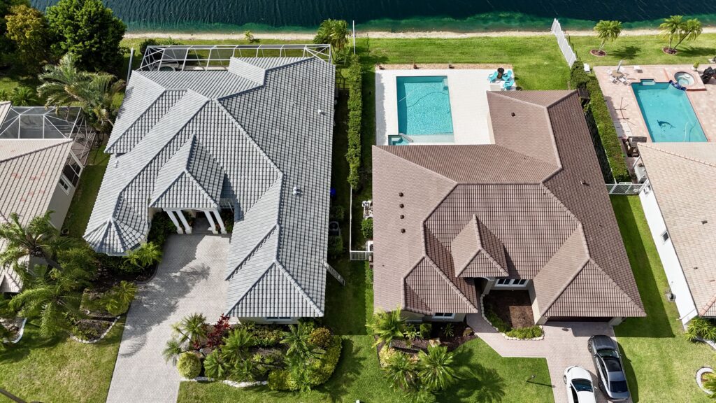 Overhead view of neighboring homes with gray and brown tile roofs and pools