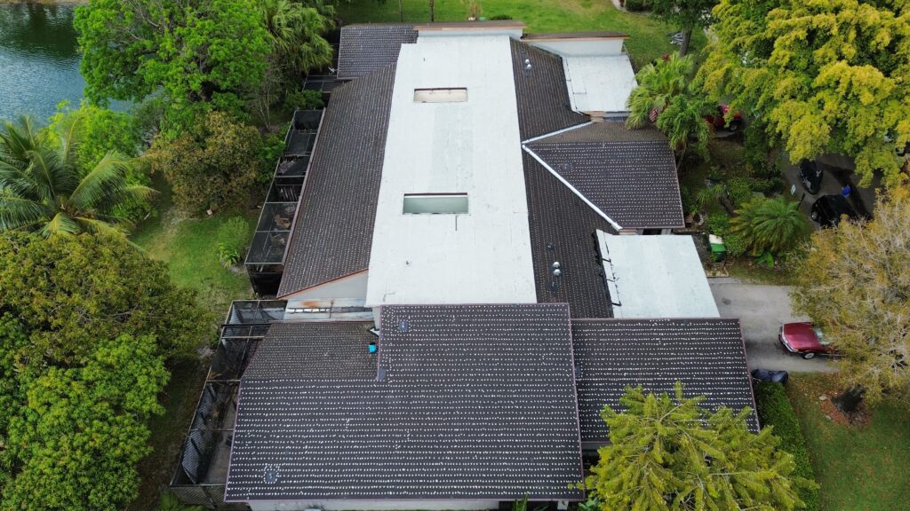 Overhead view of a home with a white flat roof section and gray shingles