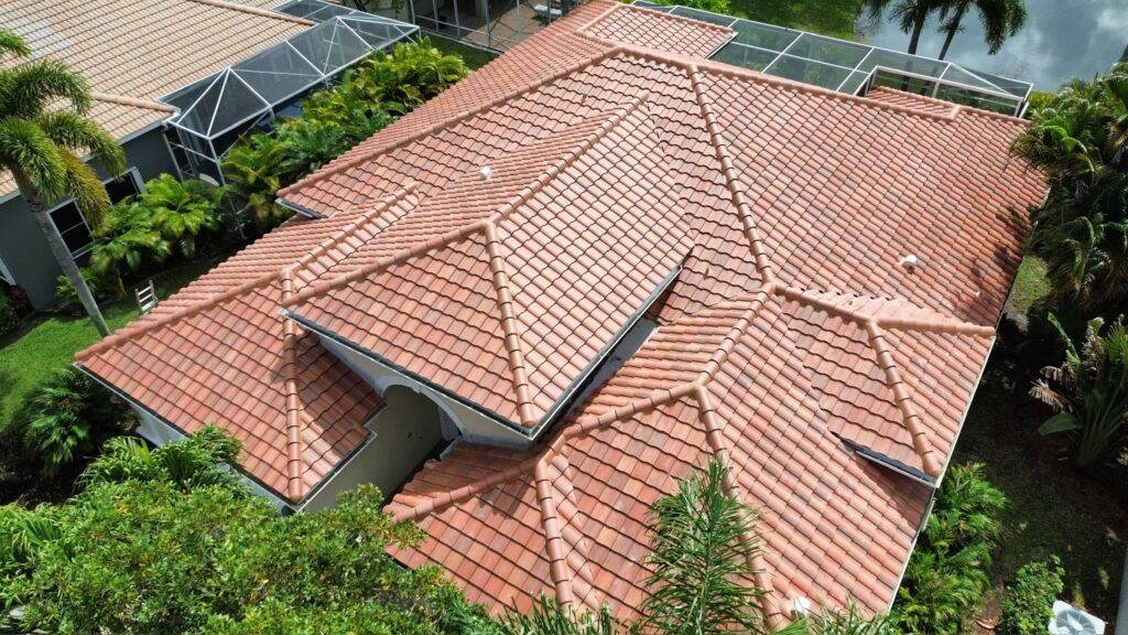 Aerial view of a home with a terracotta tile roof surrounded by trees
