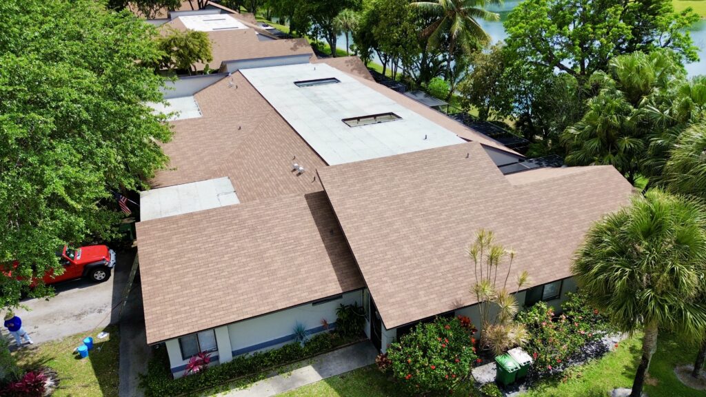 Aerial view of a home with tan shingle and flat roof sections