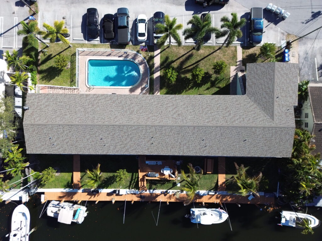 Overhead view of a gray shingle roof on a canal-front home with a pool