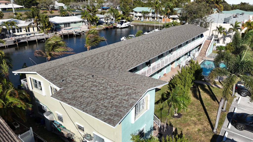 Aerial view of a long multi-unit building with a gray shingle roof