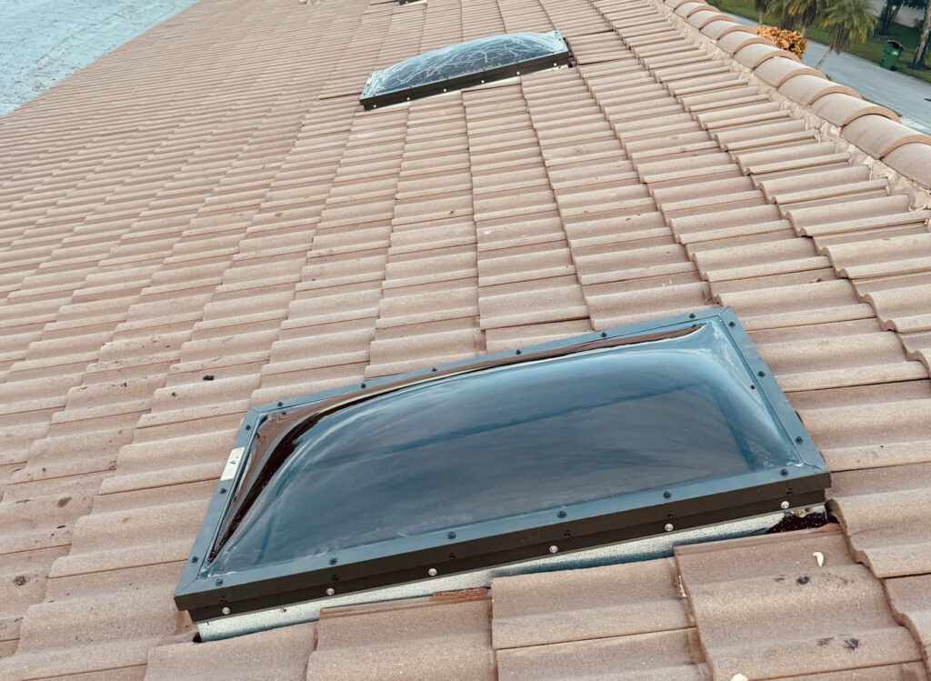 Clear dome skylight installed on a tan tile roof