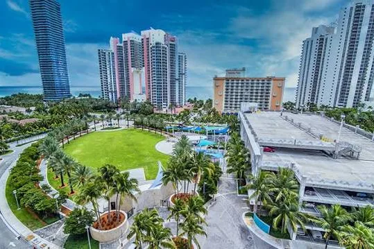 Aerial view of high-rise condominium towers and a green park in Aventura, FL
