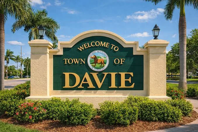Welcome to Town of Davie entrance sign framed by palm trees and flowers